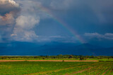 The rainbow over the cultivation fields and the majestic mountains of the Valle del Cauca region in Colombia