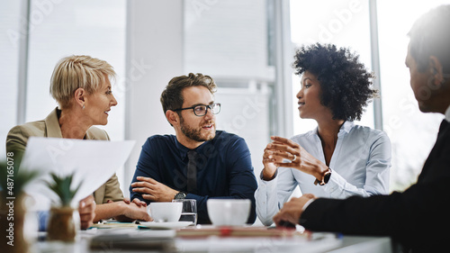 Give us difficult and well show you easy. Shot of a group of businesspeople sitting together in a meeting. photo
