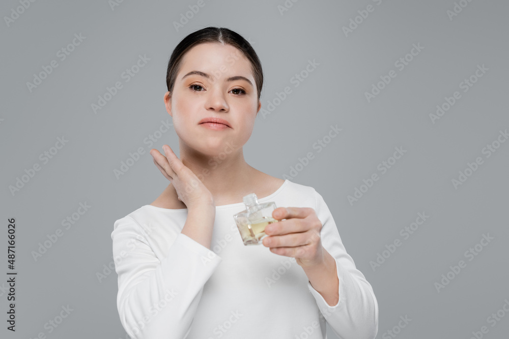 Young woman with down syndrome applying perfume isolated on grey Young woman with down syndrome applying perfume isolated on grey