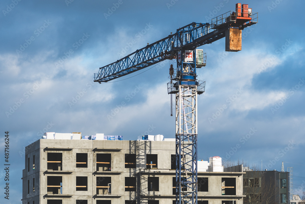 Worksite with cranes, new buildings or houses under construction with cloudy sky in the background Worksite with cranes, new buildings or houses under construction with cloudy sky in the background