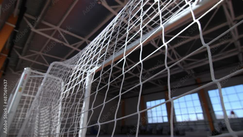 Football gates with white mesh near window in empty spacious gym of contemporary sports school extreme close view Football gates with white mesh near window in empty spacious gym of contemporary sports school extreme close view