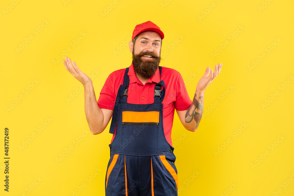 smiling bearded man repairer in work clothes on yellow background