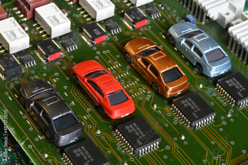 Toy cars on electronic board and microchip. Conceptual image for semiconductor shortage disrupting production of the automotive industry. photo