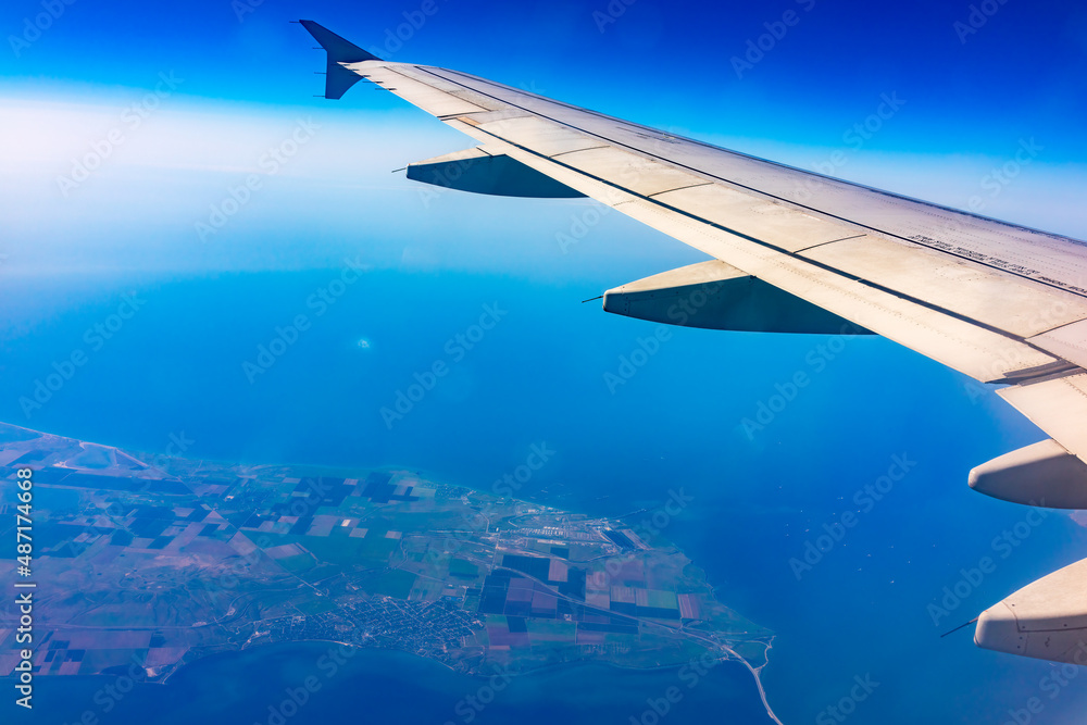 View from the airplane window at a beautiful blue clear sky, earth, sea and the airplane wing View from the airplane window at a beautiful blue clear sky, earth, sea and the airplane wing