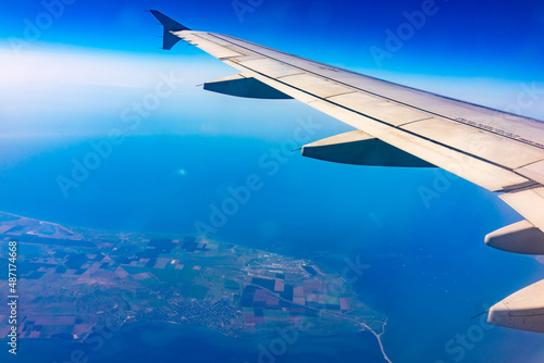 View from the airplane window at a beautiful blue clear sky, earth, sea and the airplane wing