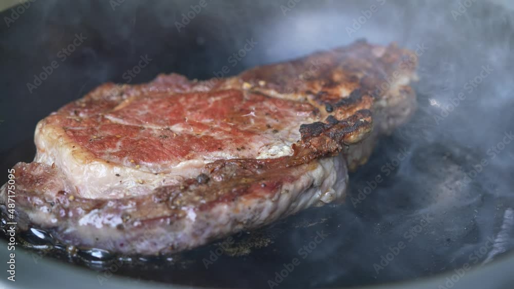 Steak meat beef being grilled on a sizzling hot plate pan with smoke. slow motion Steak meat beef being grilled on a sizzling hot plate pan with smoke. slow motion