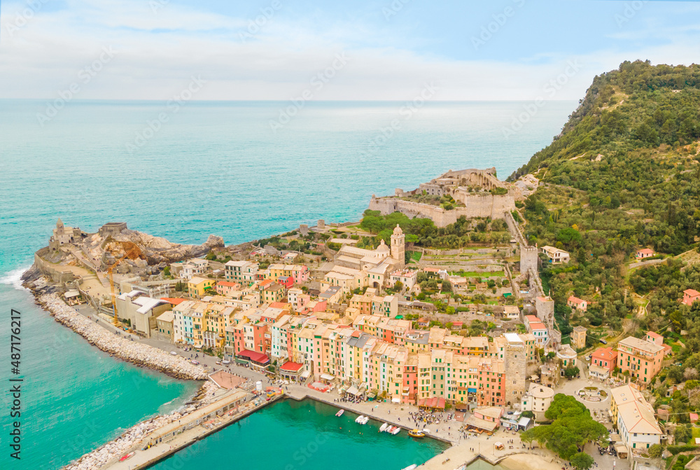 Beautiful seafront promenade of an Italian town with multi-colored facades of houses and a fortress near a mountain with green trees