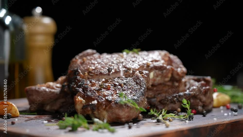 Cooked juicy steak meat beef with seasoning dropped on wooden chopping board. slow motion Cooked juicy steak meat beef with seasoning dropped on wooden chopping board. slow motion