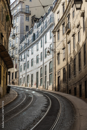 Lisbon, Portugal - 12 28 2018: Empty bending streets and railway tracks with typical old houses