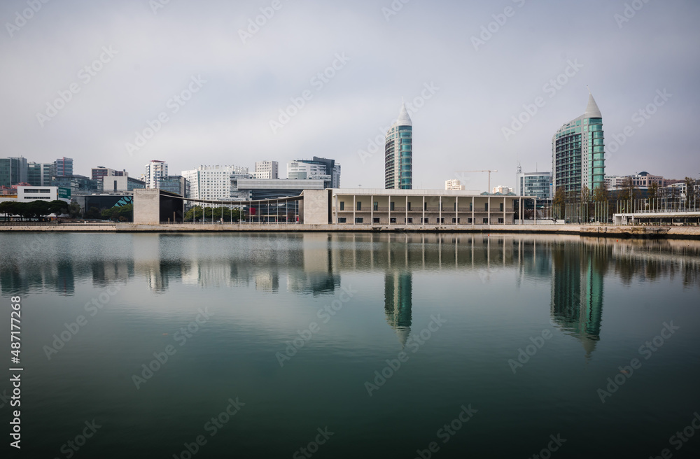 Lisbon / Portugal - 12 28 2018: Panoramic view of modern buildings and skyscrapers reflecting in the calm water of a pond