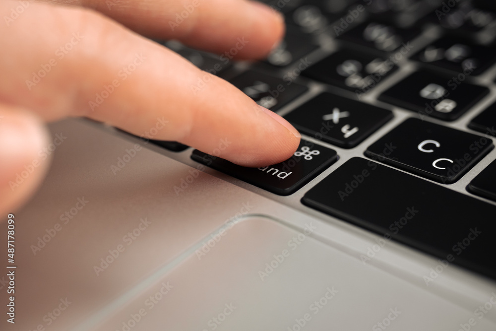 Hand pressing command key on modern laptop keyboard. Command sign and symbol close-up Hand pressing command key on modern laptop keyboard. Command sign and symbol close-up