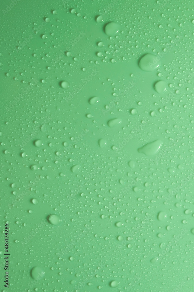 Green pastel water drops on light shiny surface