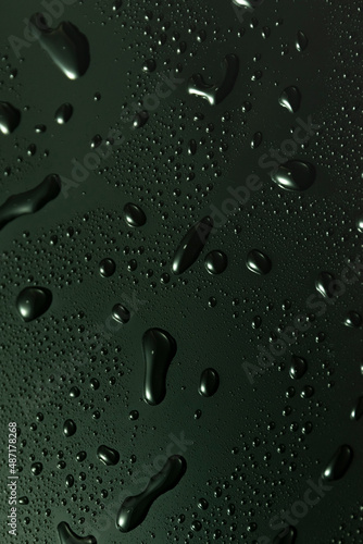 Green metal water drops on dark shiny matallic surface