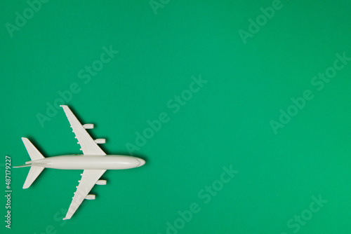 Airplane model. White plane on green background. Travel vacation concept. Summer background. Flat lay.