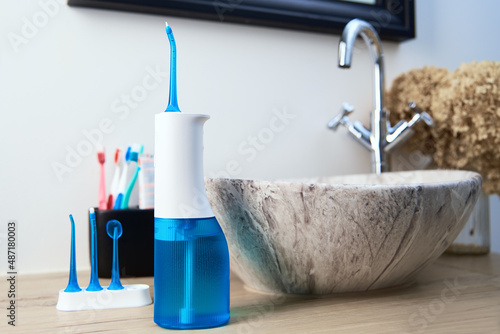 Blue home oral irrigator kit in bathroom, Waterpik for teeth cleaning, portable water flosser for dental care photo