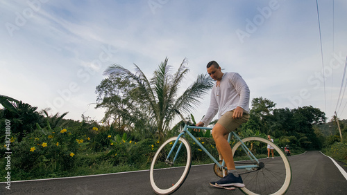 Biking road trip. The man on blue bike in white clothes on forest road. The biker men ride on bicycle. Cycling Cycle Fix. Asia Thailand ride tourism. Take a photo with a bike.