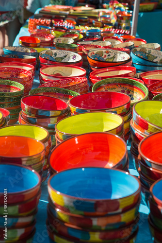 Traditional and typical ceramic bowls and dishes with patterns or decors of flowers, plants, vegetables and fruits sold at a farmers market stall in Provence, Côte d ´azur, France, blurred background © blickwinkel2511