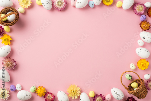 Top view photo of easter decorations field flowers and easter baskets with eggs on isolated pastel pink background with empty space in the middle