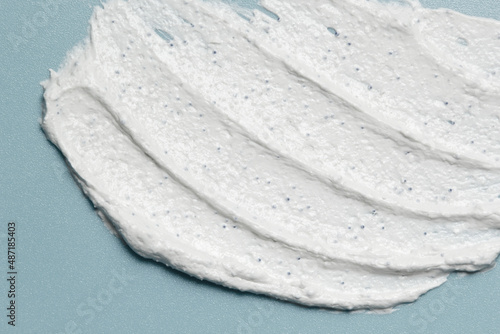 White clay salicylic acid cleanser, face mask, scrub texture. Exfoliant face wash mousse smudged on pastel blue background photo