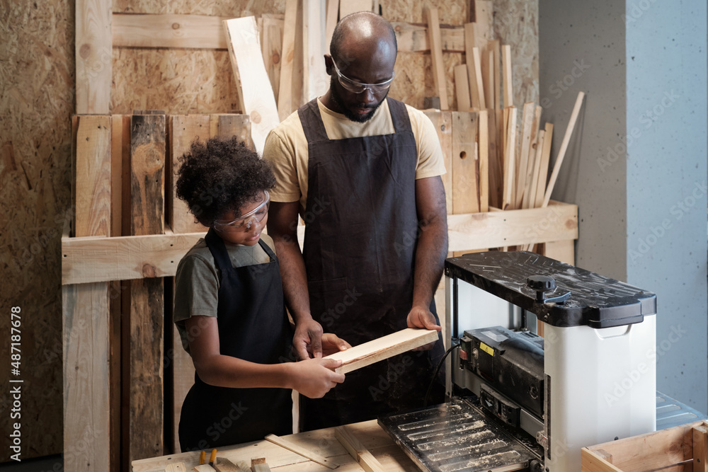 Waist up portrait of African-American father and son in enjoying work carpentry workshop together Waist up portrait of African-American father and son in enjoying work carpentry workshop together