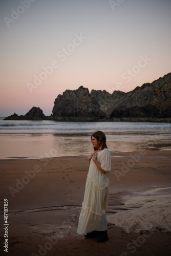 young girl enjoying the sunset on the beach in a long dress
