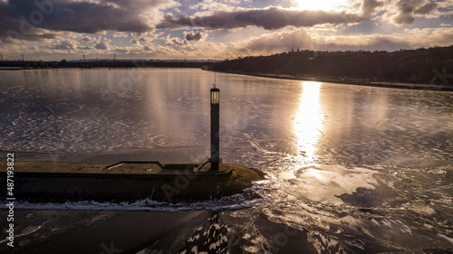 Aerial view of a pier with a lighthouse on a frozen lake