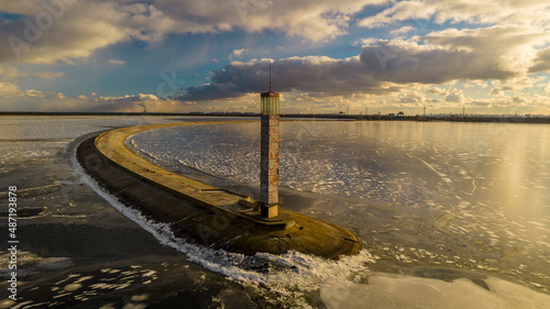 Aerial view of a pier with a lighthouse on a frozen lake