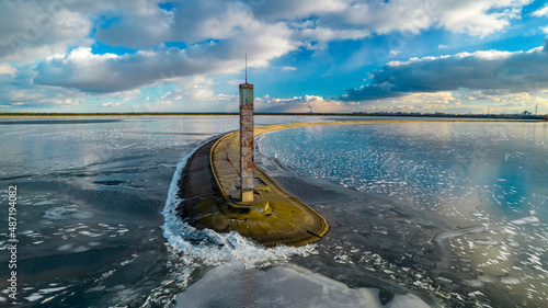 Aerial view of a pier with a lighthouse on a frozen lake