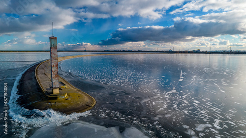 Aerial view of a pier with a lighthouse on a frozen lake