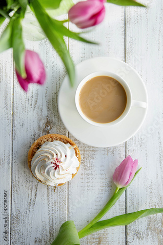 Tulips and a sweet dessert with a cup of coffee on grey wooden table,flat lay. Morning romantic breakfast.