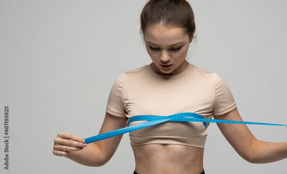 Attractive young brunette women in sportswear and takes measurements of her breasts. Measurements of a body. Sport, fitness and diet. Attractive young brunette women in sportswear and takes measurements of her breasts. Measurements of a body. Sport, fitness and diet.
