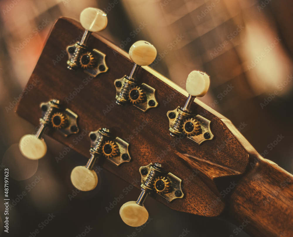 The neck of an acoustic guitar with a closeup tuning mechanism. The