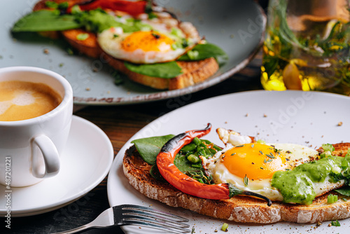 hearty and high-calorie breakfast. delicious and mouth-watering bruschetta with fried eggs and herbs for breakfast with a cup of aromatic coffee.