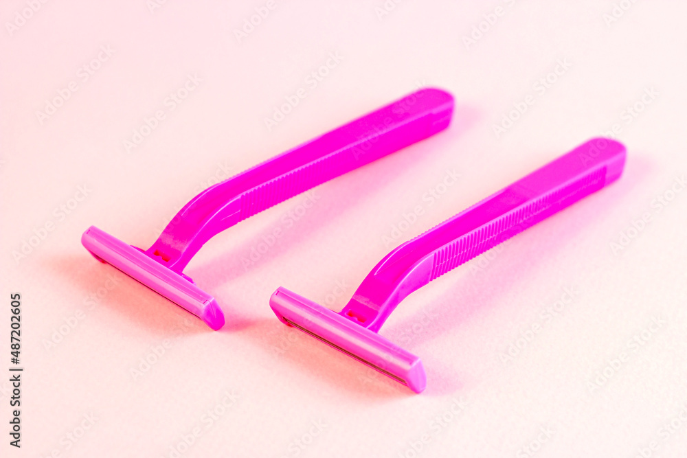 Pink disposable woman razors on light pastel background. Hair removing, epilation procedure and shaving concept.