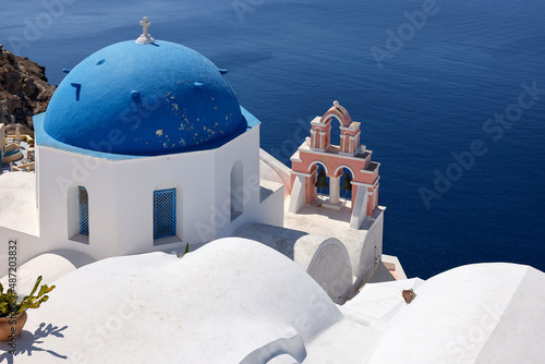 View from viewpoint of Oia village with blue dome of greek orthodox Christian church. Santorini, Greece