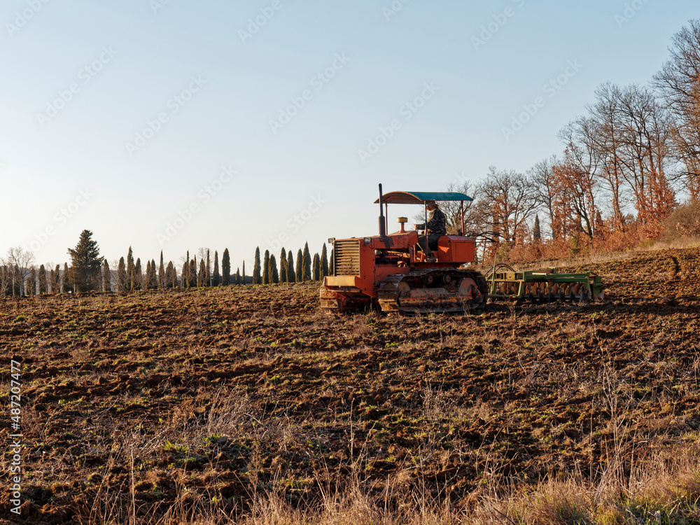 Fototapeta premium Agriculture,tractor preparing land with seedbed cultivator as part of pre seeding activities in early spring season of agricultural works at farmlands.