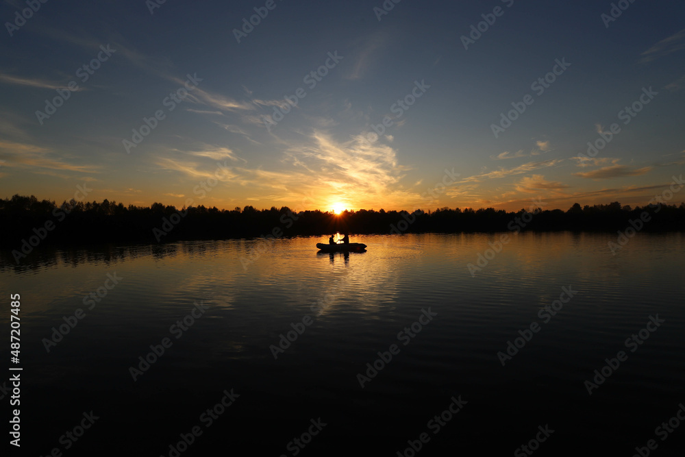 two people in a boat on the lake are sailing at a beautiful sunset