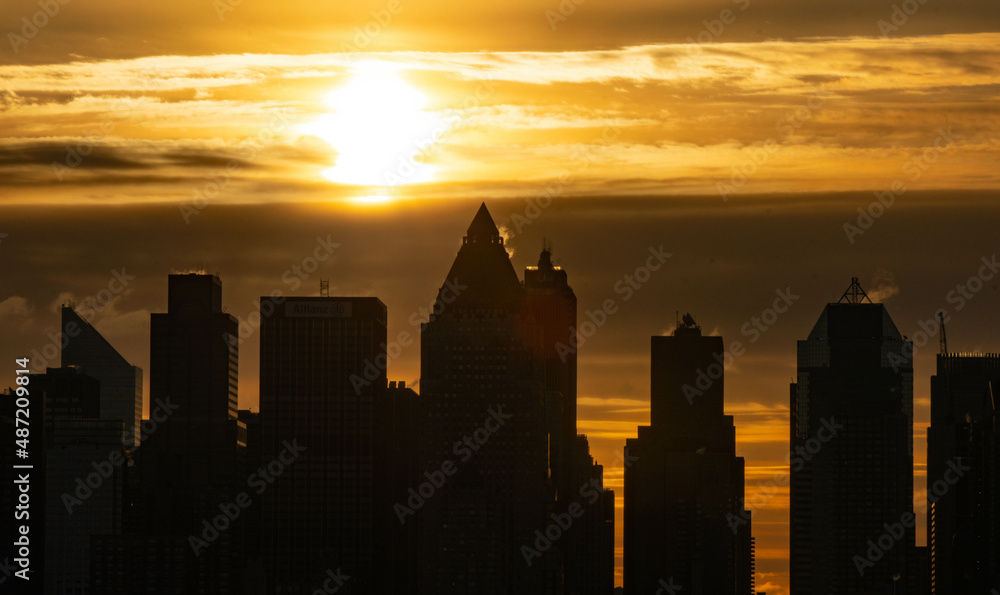Stunning morning sunrise over Manhattan skyline in silhouette and vivid sky-clouds.