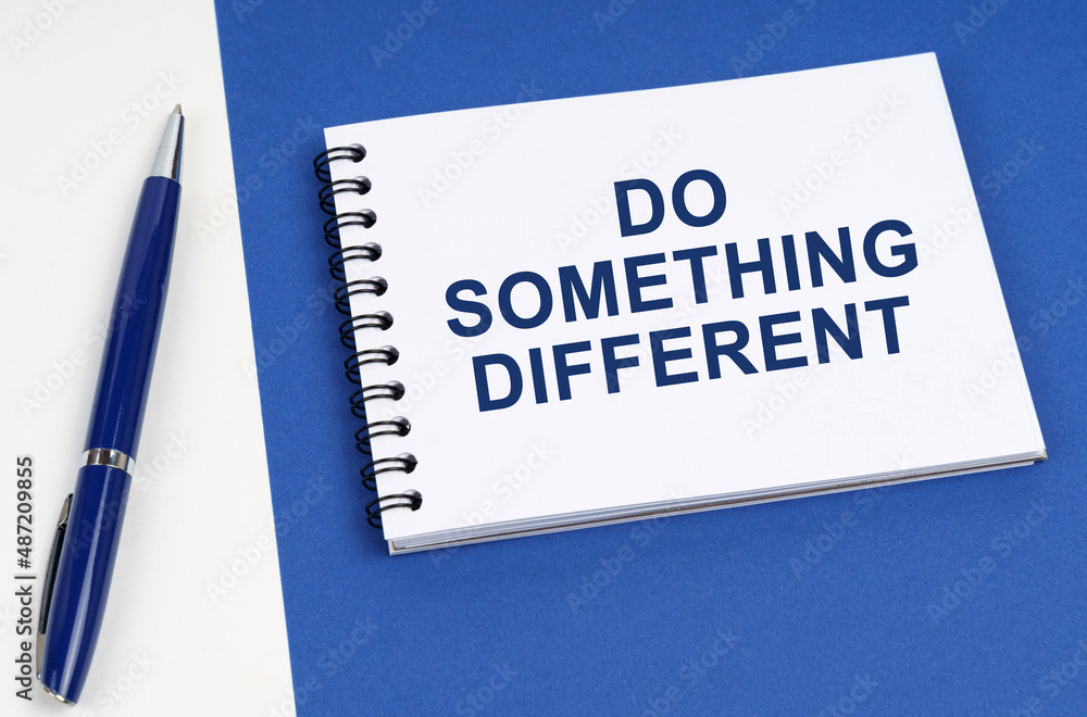 On a blue-white surface lies a pen and a notebook with the inscription - Do Something Different On a blue-white surface lies a pen and a notebook with the inscription - Do Something Different