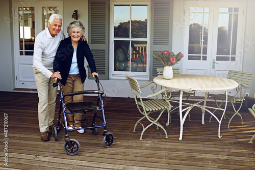 Theyll always support each other. Portrait of a smiling senior woman using a walker with her husband beside her outside their home. photo