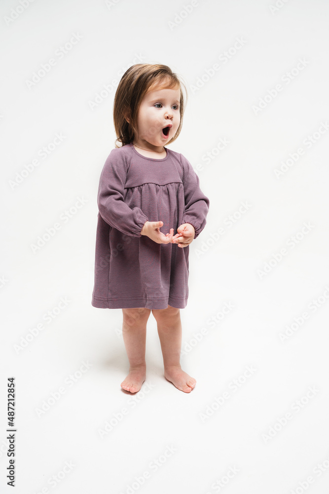 Vertical photo with a child in a purple dress. The baby sings the song on a monochromatic background. The girl performs with songs and dances Vertical photo with a child in a purple dress. The baby sings the song on a monochromatic background. The girl performs with songs and dances