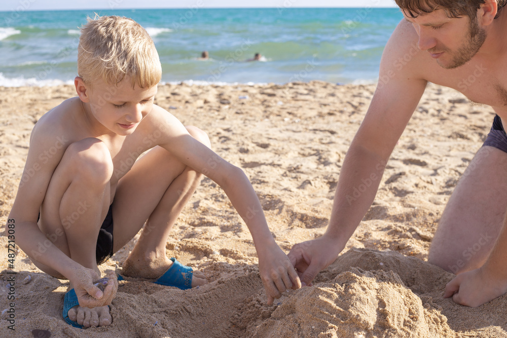 A child with his father play on the seashore in the sand. Summer holidays, family travel A child with his father play on the seashore in the sand. Summer holidays, family travel