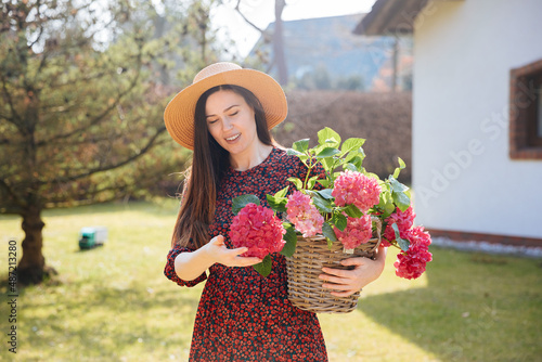 Obraz na plátně A young horticulturist holds a red hydrangea and smiles