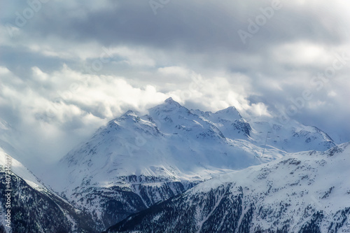 Snow covered Alps peak with cloudy sky background during winter day. © Goran