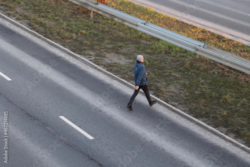 Pieszy przebiega przez jezdnię samochodową w niebezpiecznym miejscu. 