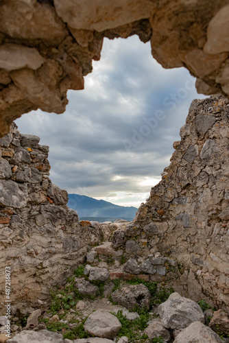 The view from abandoned stone house window hole. View from window to blue sea and cloudy sky.