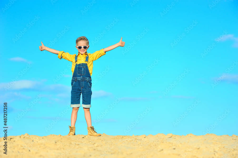 Little boy with arms spread against the blue sky. Little boy with arms spread against the blue sky.