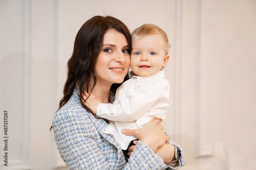 a beautiful dark-haired woman holds a one-year-old boy in her arms. 