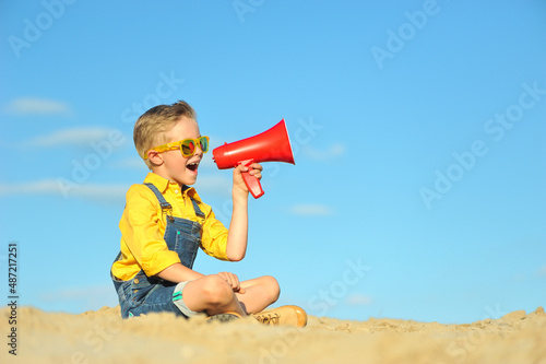 Little boy with a megaphone against the blue sky.