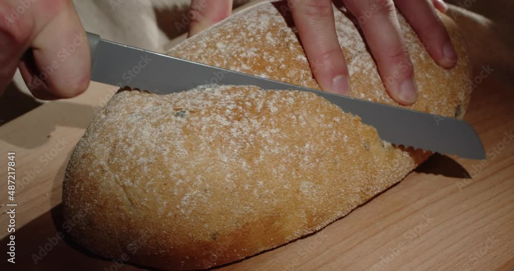 Use a sharp knife to cut a piece of freshly baked homemade bread a wooden board Use a sharp knife to cut a piece of freshly baked homemade bread a wooden board